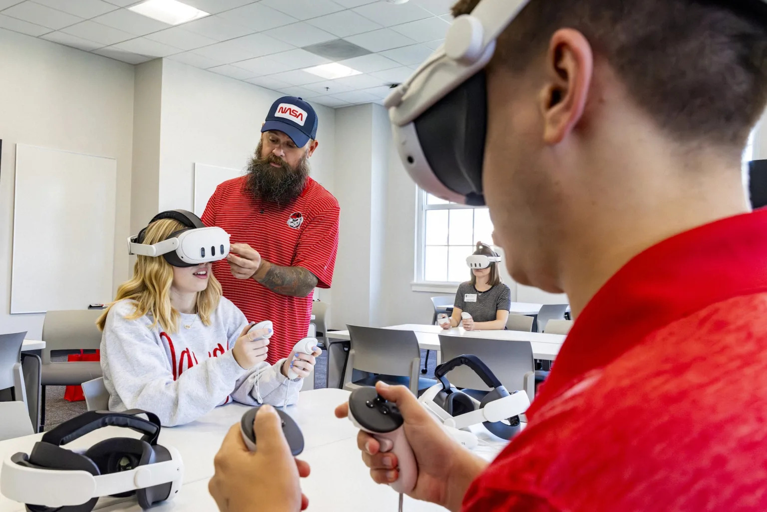 UGA students sit at a table while wearing and using virtual reality headsets.