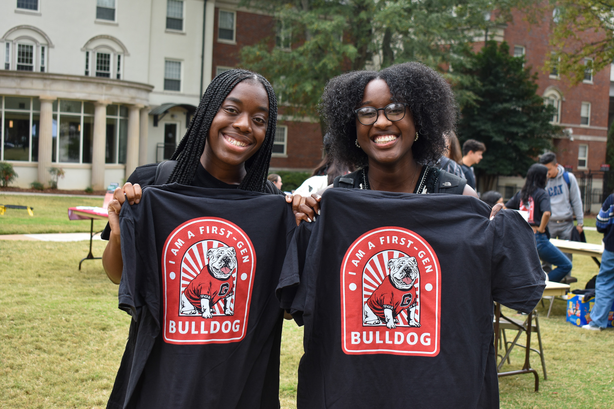 Two UGA students hold up t-shirts that say "I'm a first-gen dawg."