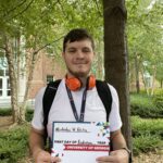 Student with backpack holding sign