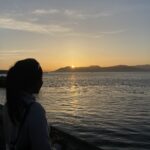 Girl looking over lake at sunset.