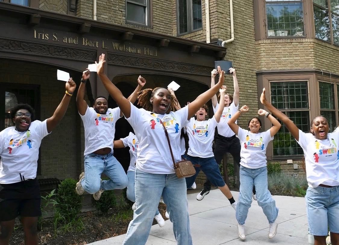 Several high school students jump in the air in a celebratory manner